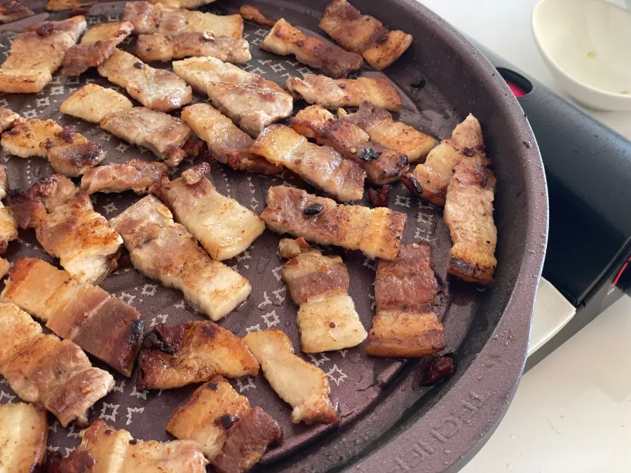 alt="Perfectly grilled Korean BBQ samgyeopsal (pork belly) cut into bite-sized pieces"