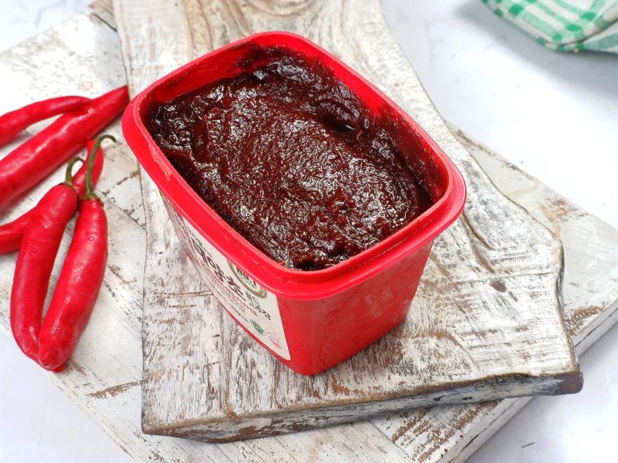 alt="Gochujang red chili paste in a store-bought container"
