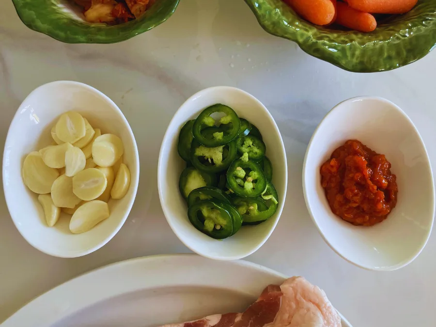 alt="Garlic, chili peppers, and ssamjang in small Dowan bowls for sauces and banchan"