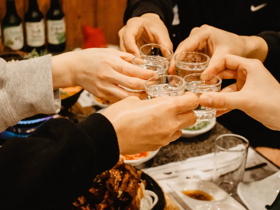 alt="People toasting with soju glasses"