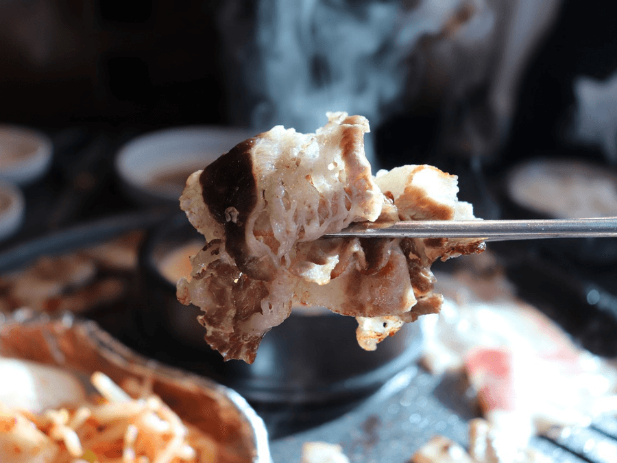 alt="Chopsticks picking up a piece of grilled meat"  
