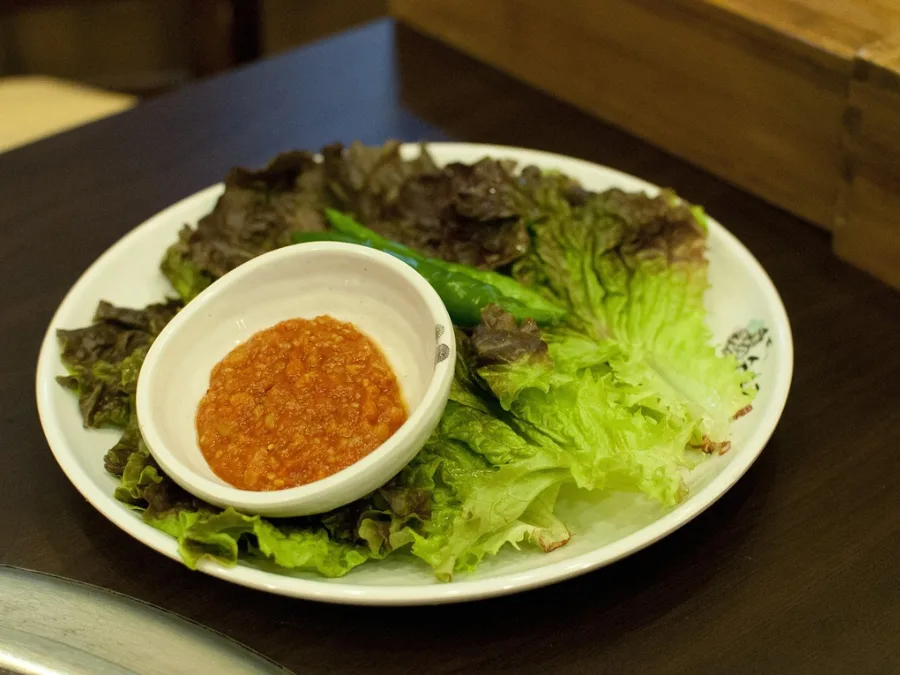 alt="Lettuce, chili peppers, and ssamjang on a plate for Korean BBQ wraps"
