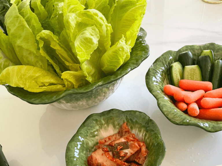 alt="Assorted lettuce wraps, cucumber, carrot, and kimchi in a cabbage-shaped bowl set"