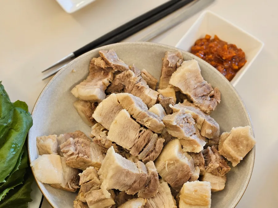 alt="Pork belly samgyeopsal and ssamjang dipping sauce in the background"