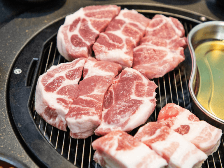 alt="Pork neck (moksal) placed on a Korean BBQ grill"