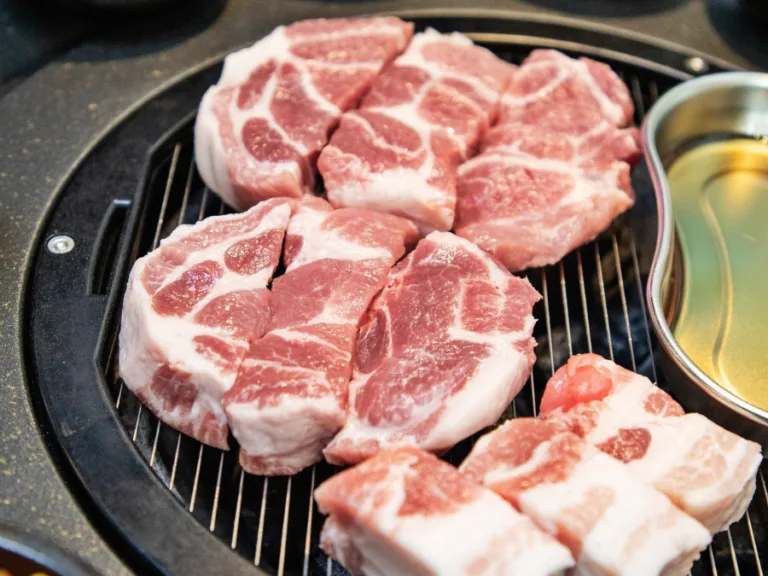 alt="Pork neck (moksal) placed on a Korean BBQ grill"