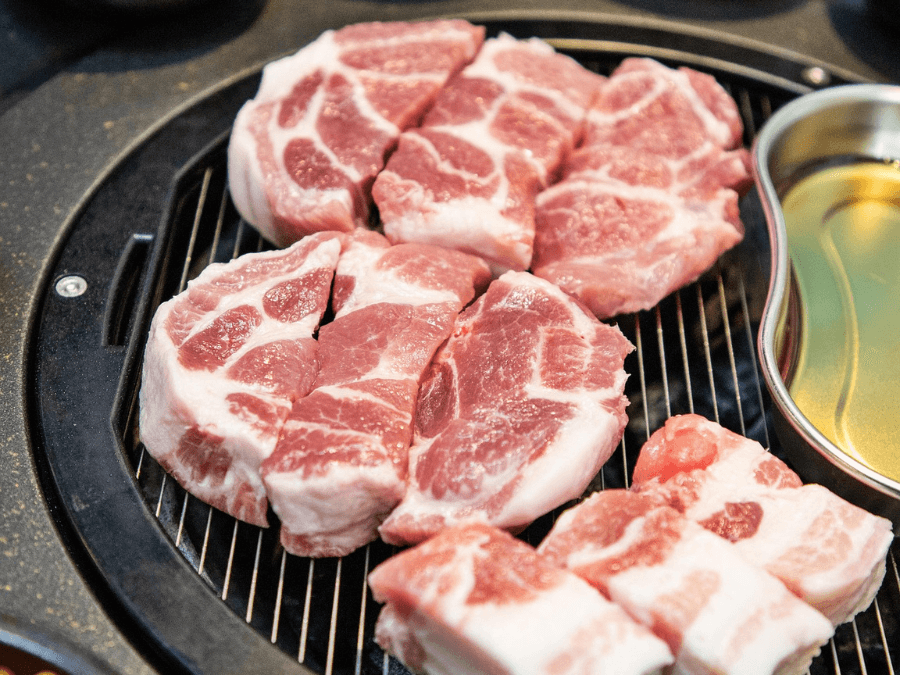 alt="Pork neck (moksal) placed on a Korean BBQ grill"